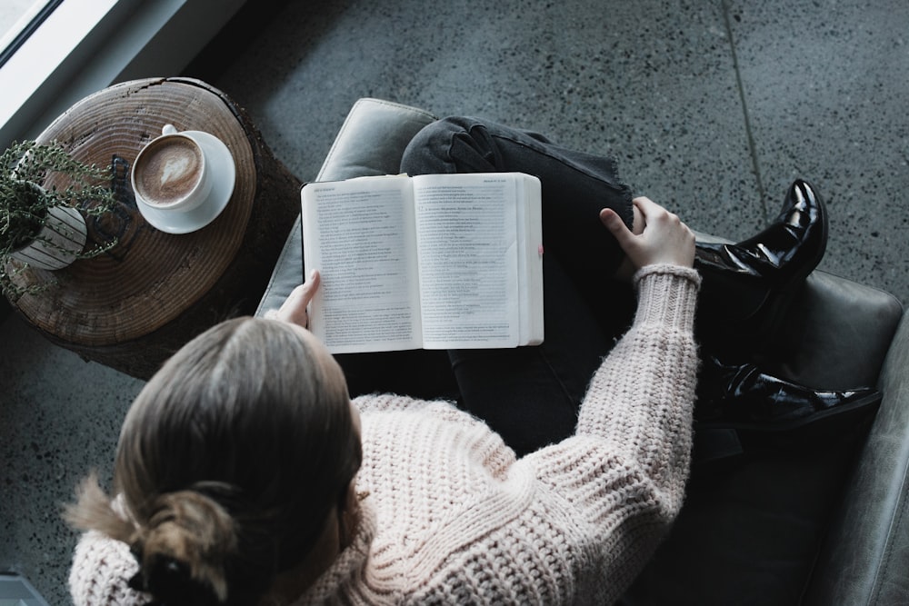 mujer en suéter blanco leyendo libro