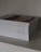 A stack of neatly arranged religious books with white covers displayed on a shelf, each titled with a different book of the Bible.