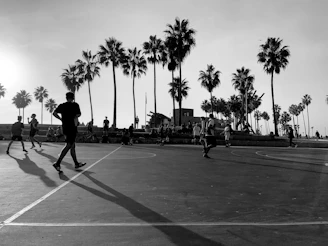 A group of smiling volunteers coaching kids on a basketball court during a sunny afternoon.