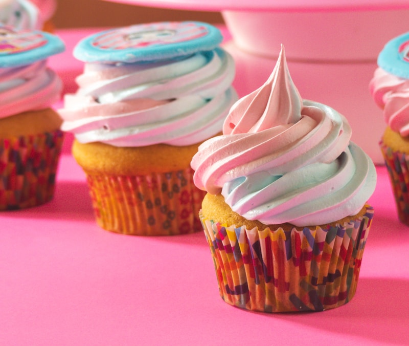 Frosted cupcakes with sprinkles on a pink background