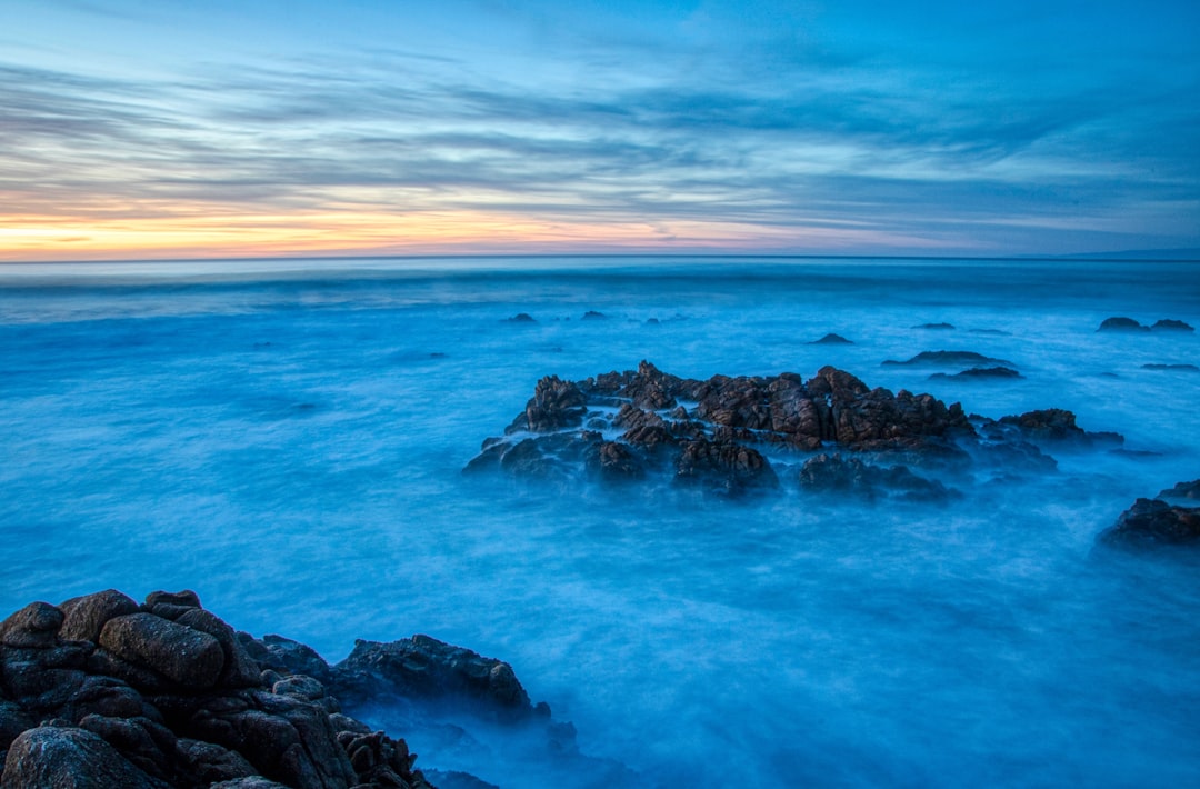 brown rock formation on sea under blue sky during daytime