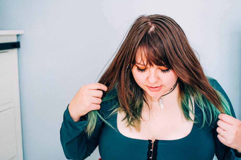 mulher na camisa verde de manga comprida segurando seu cabelo