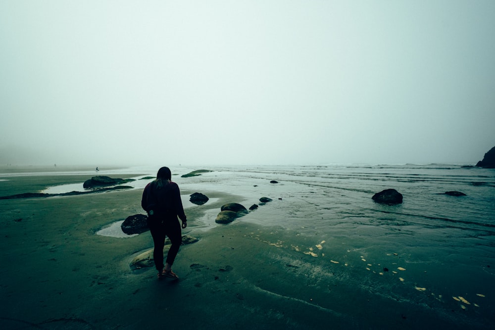 man in black shirt and pants standing on seashore
