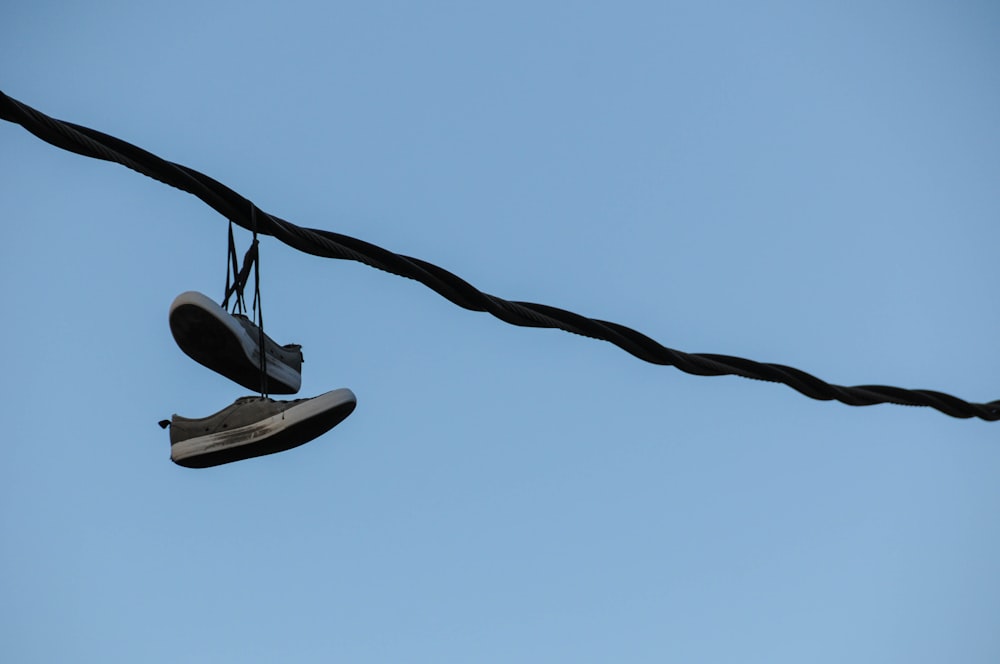 person in black and white sneakers jumping on brown rope during daytime
