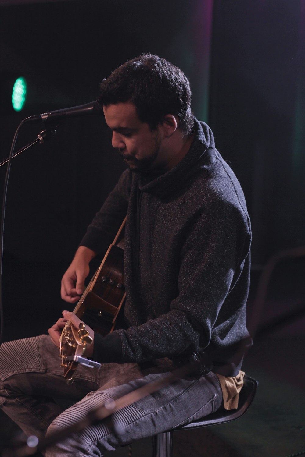 man in gray sweater playing guitar