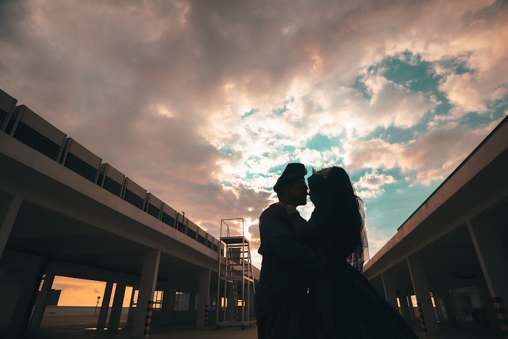 silhouette of woman standing near railings under cloudy sky during daytime