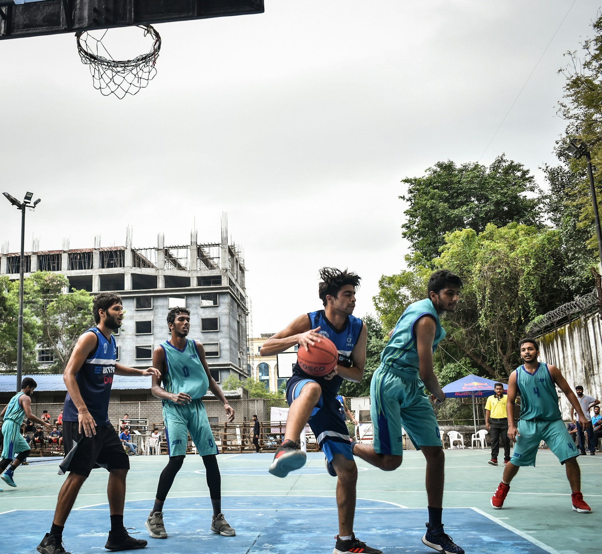 Young players fiercely competing in a fast-paced 3v3 basketball game under bright fall skies at Bacot Park.