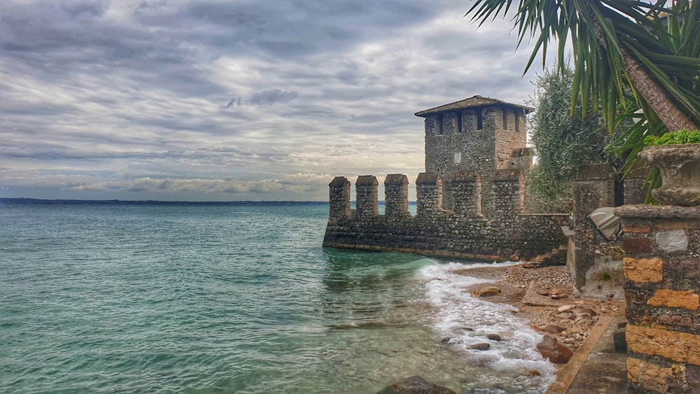 brown concrete building near sea under cloudy sky during daytime