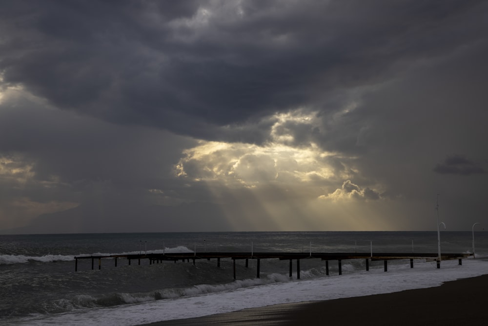doca de madeira marrom no mar sob o céu nublado durante o dia