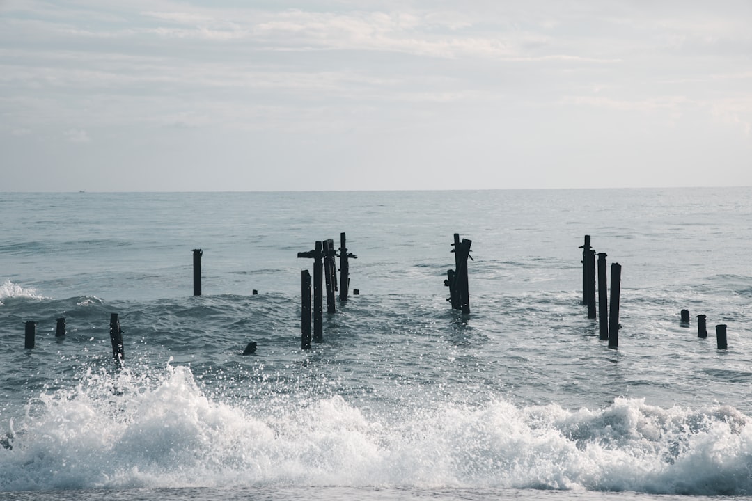 sea waves crashing on wooden dock during daytime