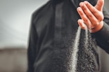 Two hands releasing a handful of sand, signifying letting go.