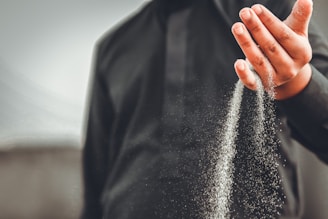 Close-up of hands releasing sand, symbolizing letting go of stress and emotional pain.