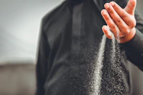Close-up of hands releasing a handful of sand symbolizing letting go.