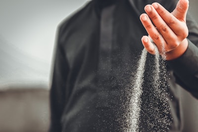 Close-up of hands gently releasing a handful of sand, representing letting go.
