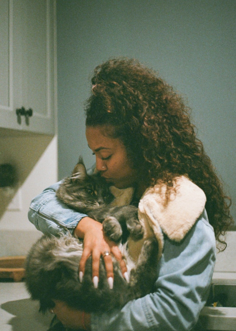 Femme en veste bleue et blanche portant un chat noir et blanc