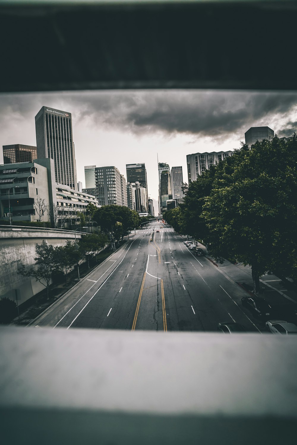 grayscale photo of road between high rise buildings