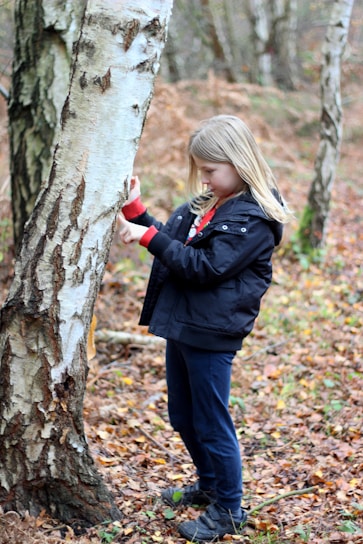 woman in black jacket and black pants standing beside tree