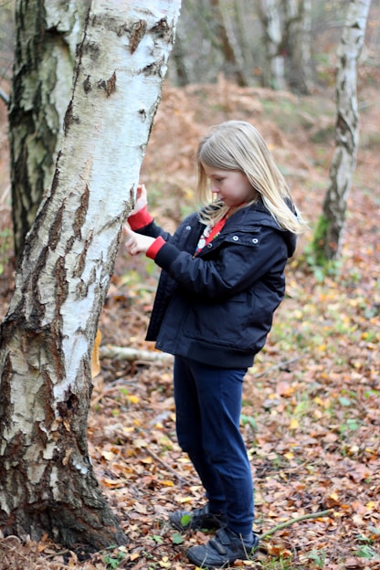 girl in black jacket and black pants standing beside tree