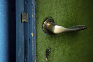 Technician in blue uniform repairing a modern front door with visible before-and-after effects.