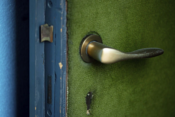 Technician in blue uniform repairing a modern front door with visible before-and-after effects.