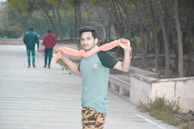 A man wearing a deep blue cottonhue scarf casually walking through an autumn park.