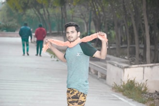 A man wearing a deep blue cottonhue scarf casually walking through an autumn park.