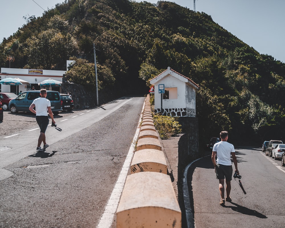 people walking on road near white and brown house during daytime