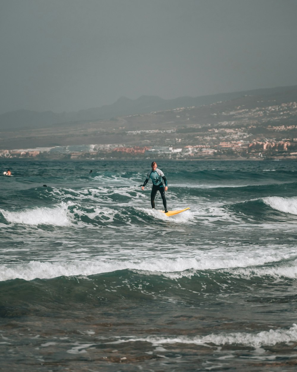 man in black wet suit surfing on sea waves during daytime