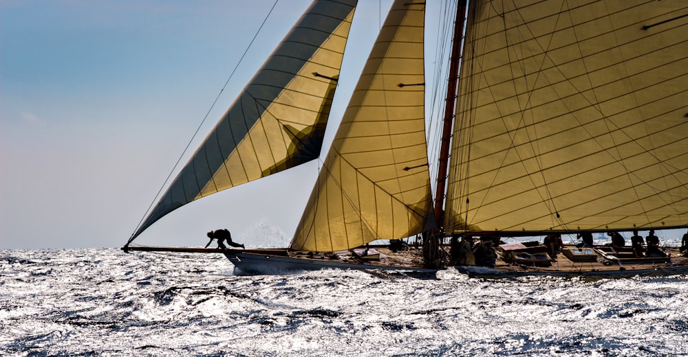 person in black shirt sitting on white sail boat during daytime