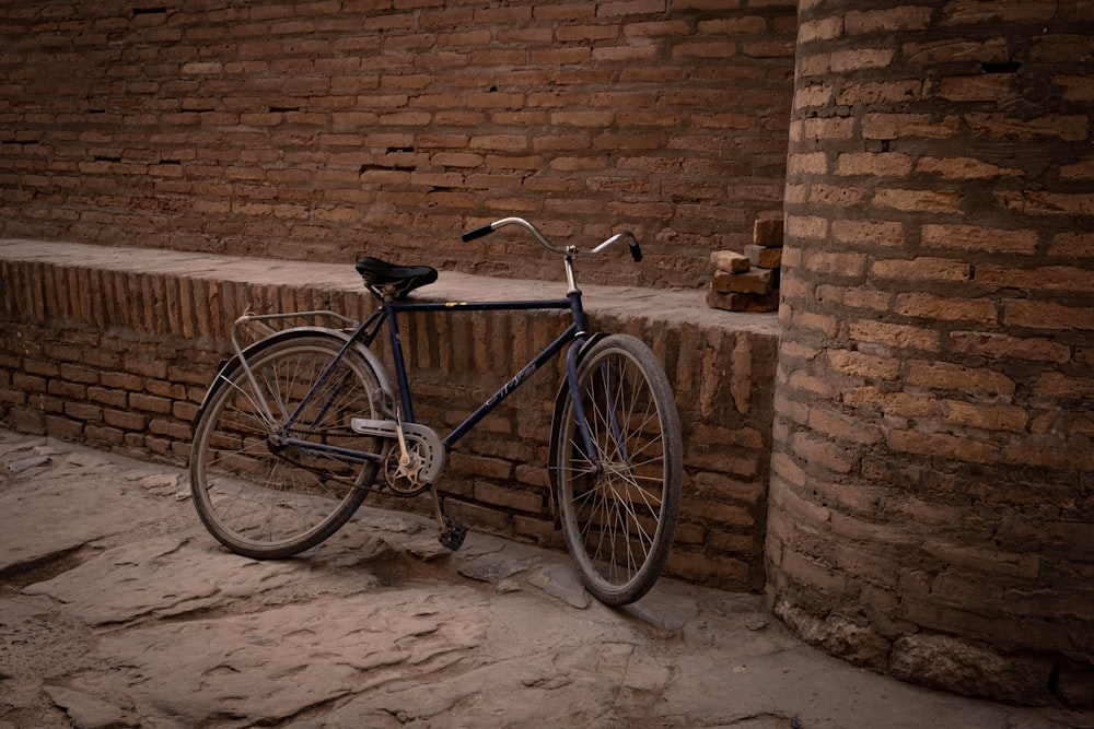 black city bike parked beside brown brick wall