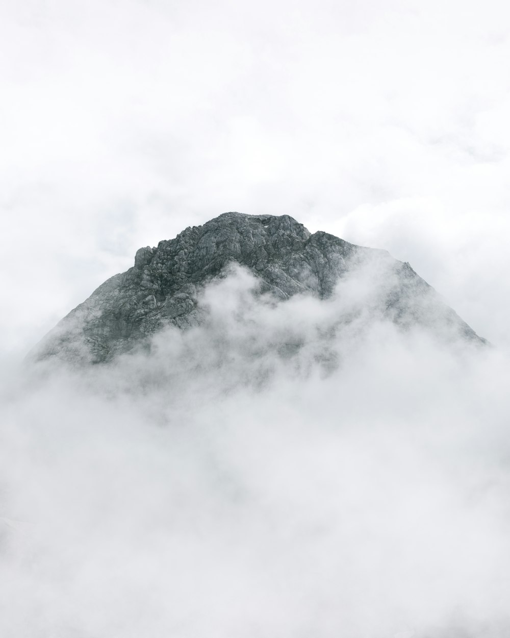 black and white mountain under white clouds