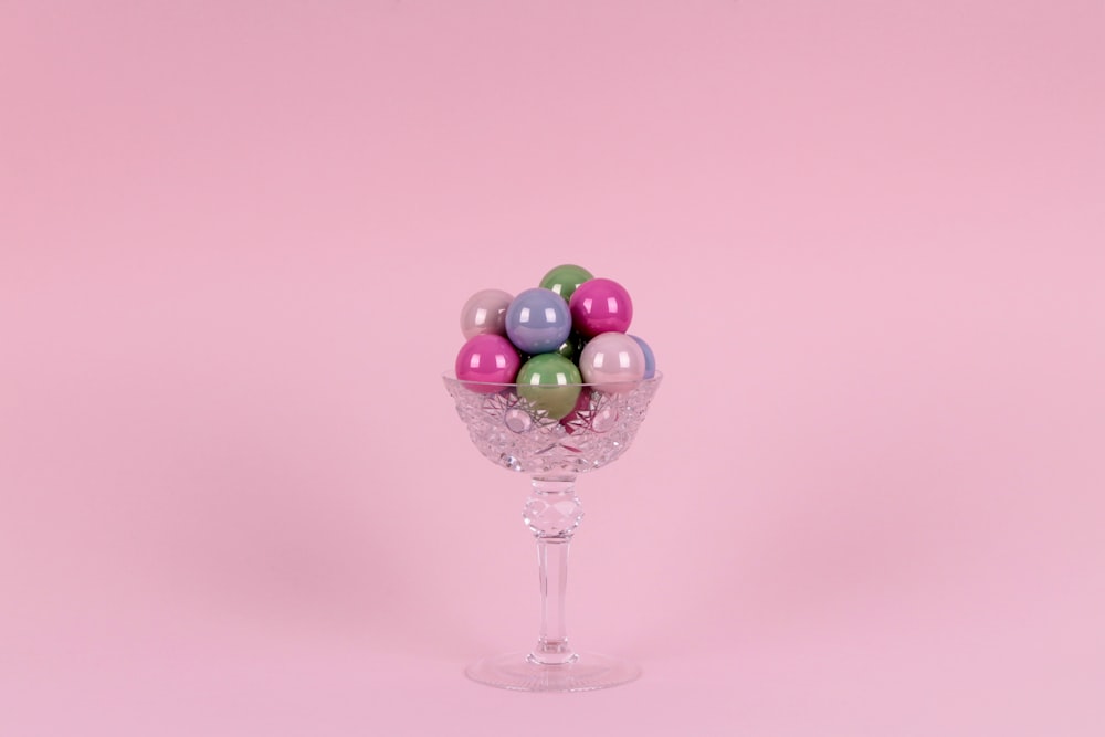 Ballons violets et verts sur bol sur pied en verre transparent