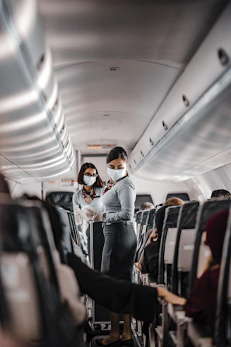 A cabin crew member demonstrating safety procedures inside an airplane cabin.