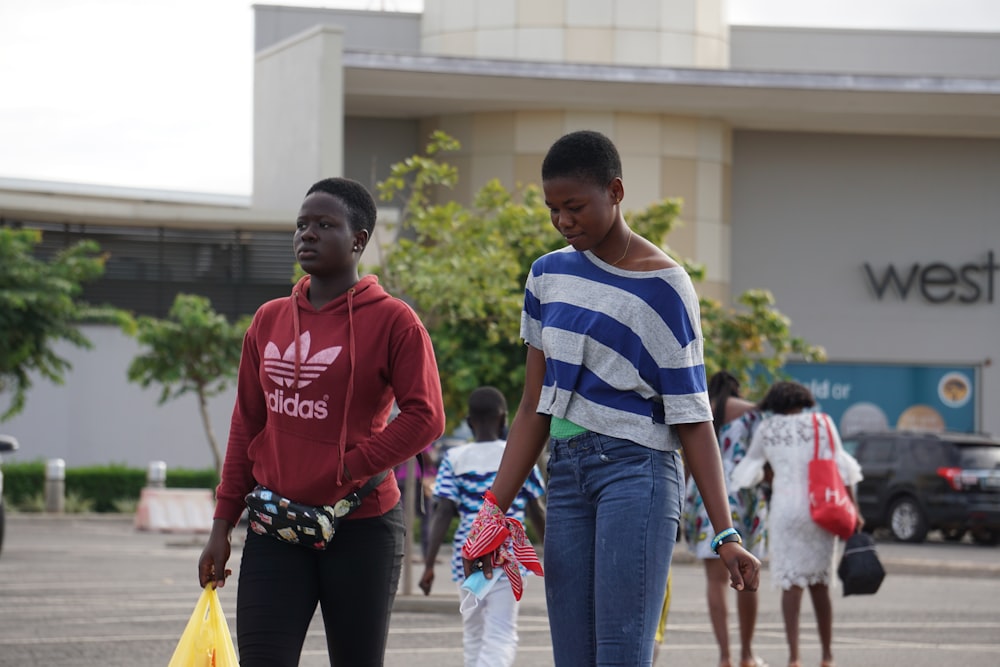 man in red and white crew neck shirt standing beside boy in blue denim jeans during