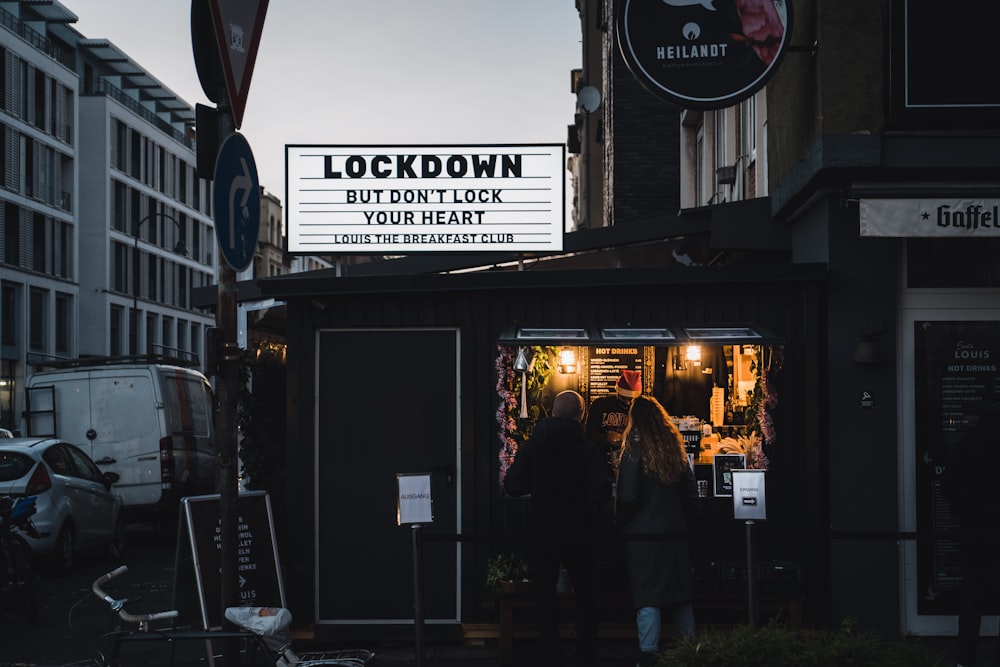 man in black jacket standing in front of store during night time