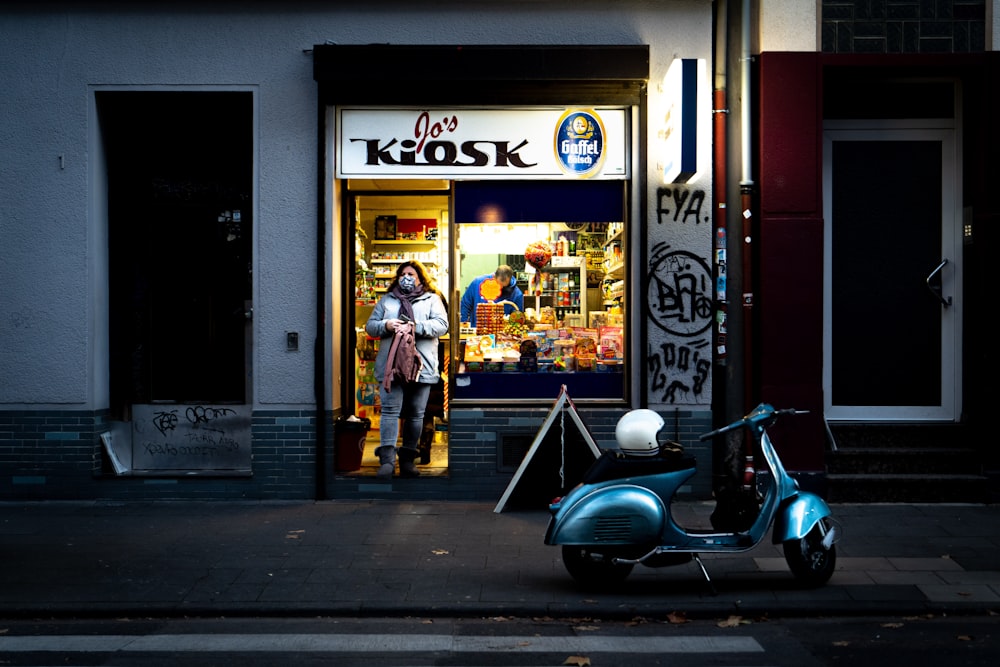 man in yellow jacket standing beside black motor scooter during daytime