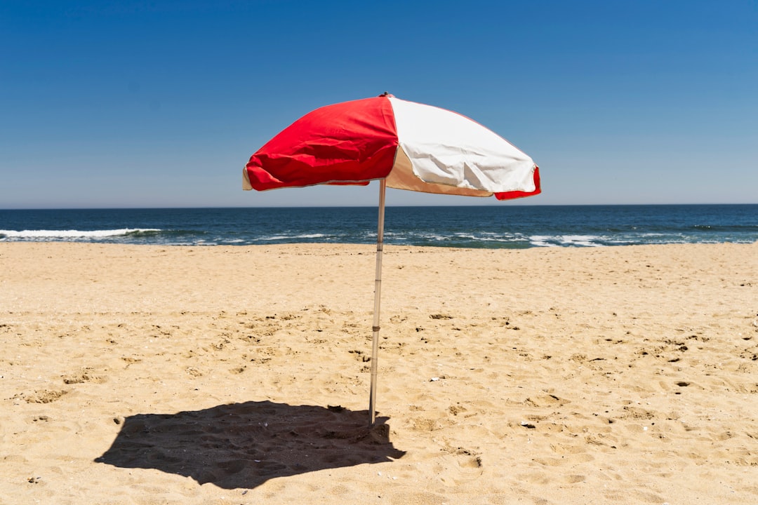 red and white umbrella on beach during daytime