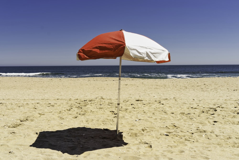 sombrilla roja y blanca en la playa durante el día