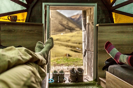 person in green pants and black leather boots sitting on chair