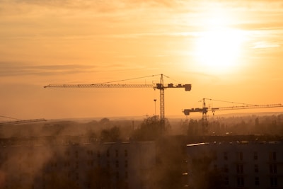 Sunset view of cranes silhouetted against the orange sky.