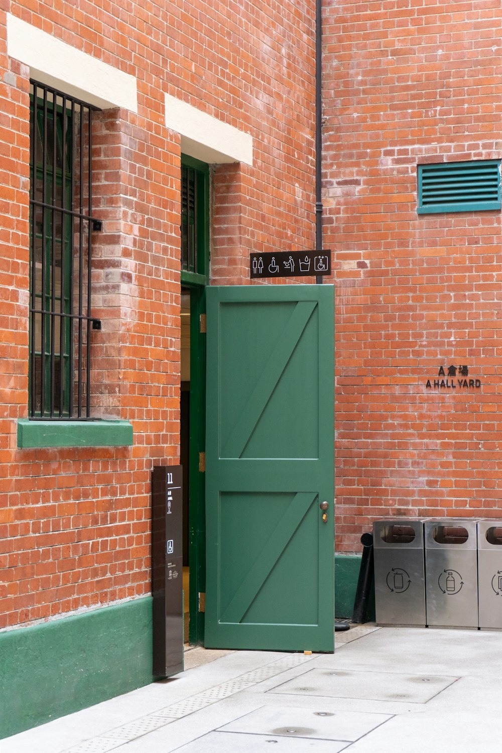 green wooden door beside brown brick wall