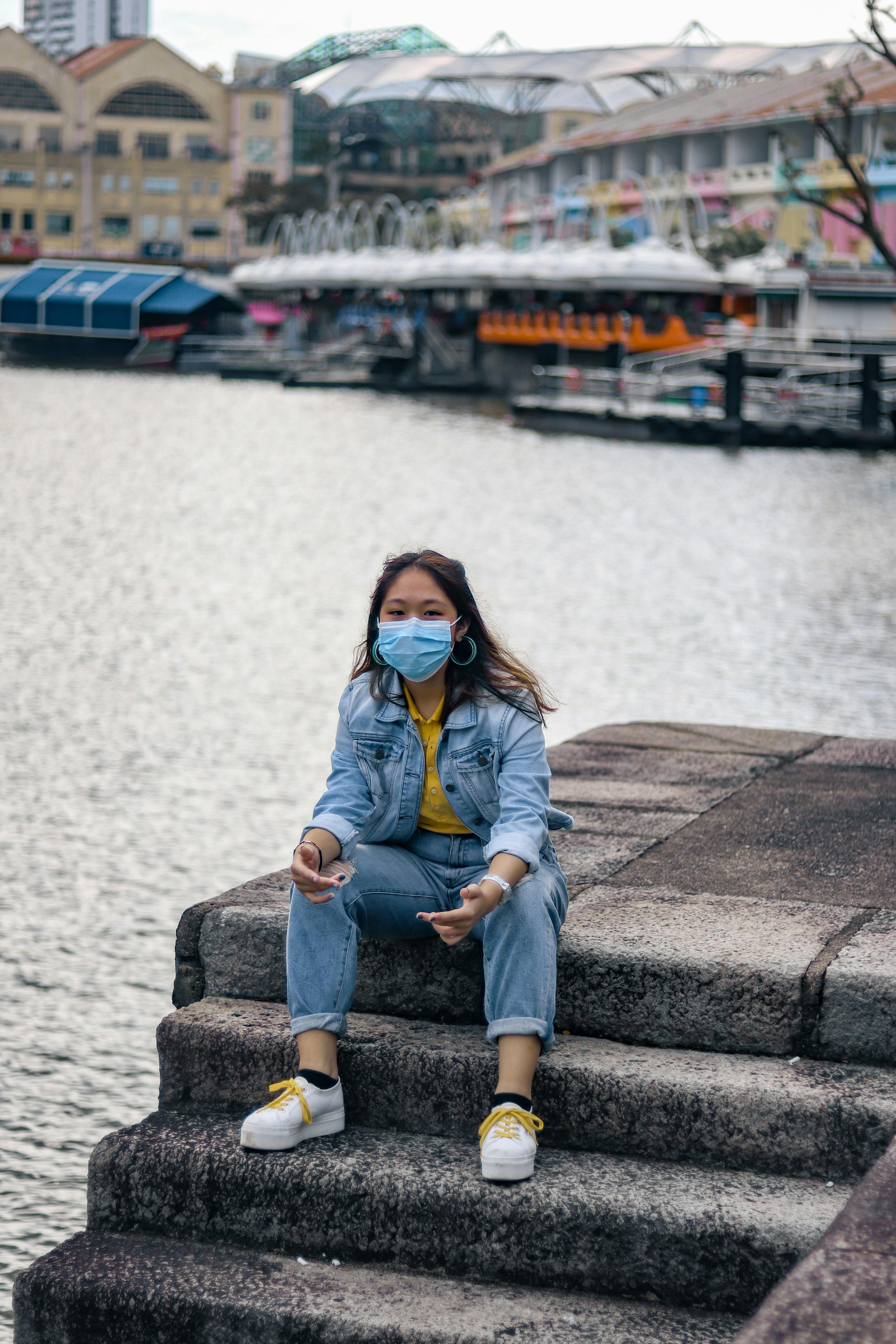 woman in blue denim jacket and blue denim jeans sitting on concrete bench