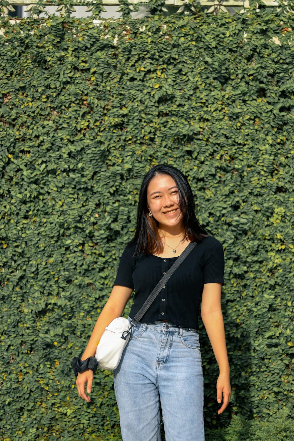 woman in black shirt and blue denim shorts sitting on green grass field