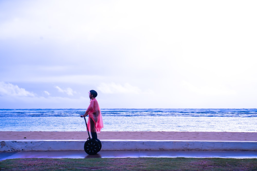 man in red shirt and black pants standing on beach shore during daytime