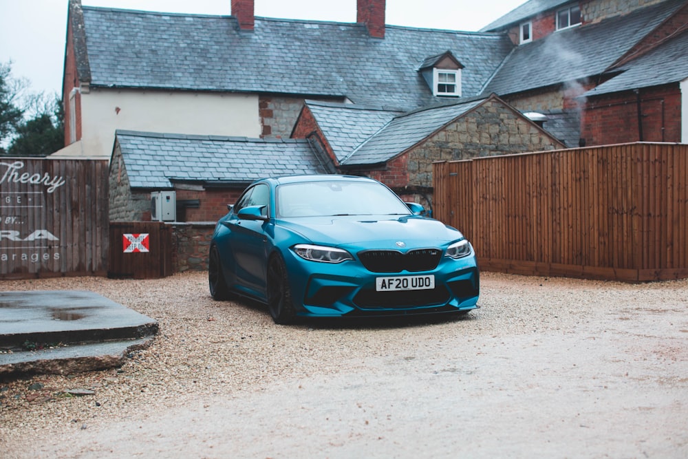 blue bmw m 3 parked near brown wooden fence