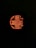 A glowing, spiral-shaped heating element is visible through a dark grid. The element emits a bright orange light, illuminating the surrounding area against a dark background.