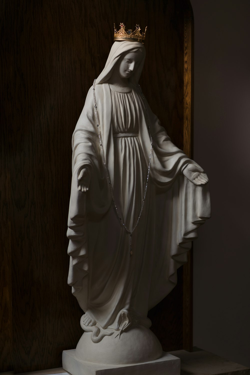 white ceramic statue on brown wooden wall
