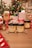 A festive scene with Christmas decorations, including a decorated tree with colorful lights. Various wrapped gifts, predominantly red and white, are arranged around products labeled as hemp extract dog chews and tinctures. The setting is cozy with a wooden table surface.