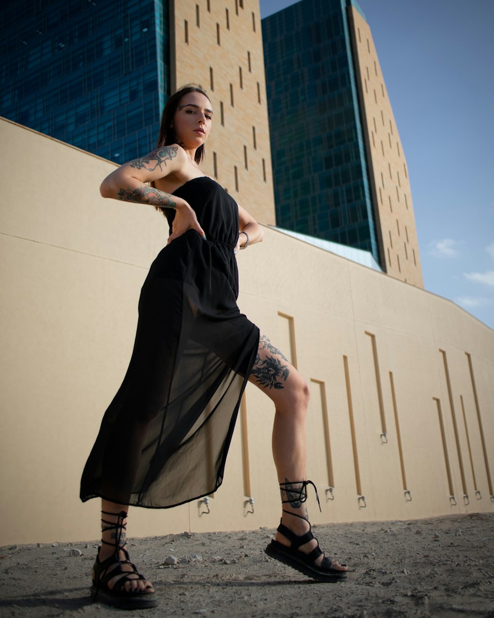 woman in black dress and brown boots standing on gray concrete floor during daytime