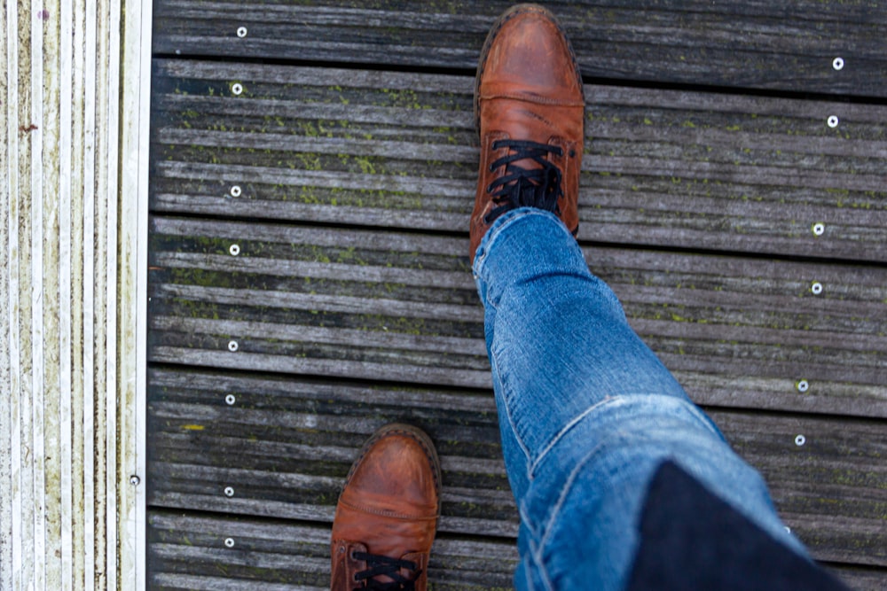 person in blue denim jeans and brown leather shoes